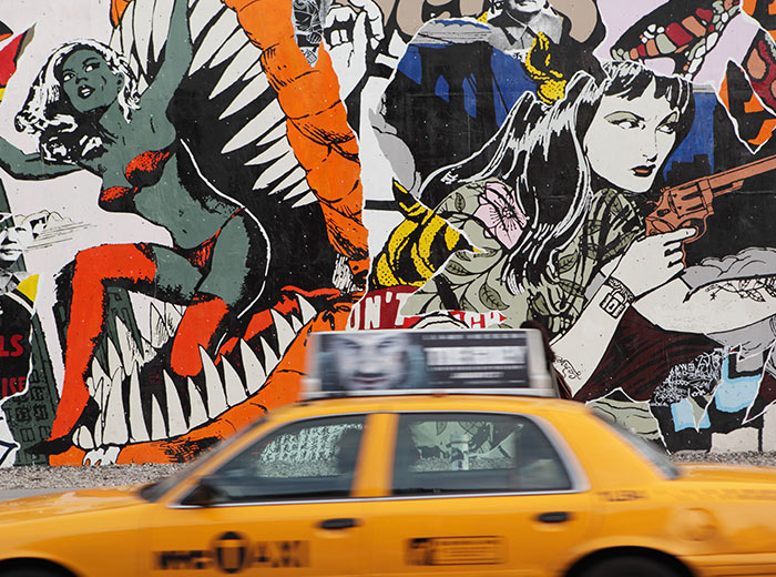 A taxi driving past wall graffiti