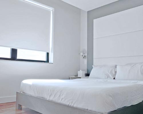 A bed with white sheets and white zig zag pillows